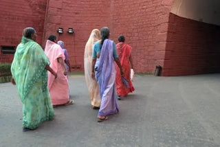 People walking beside a red building in an archived India travel photograph.