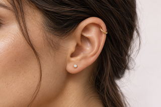 Illustrative healed-ear styling with a small gold helix hoop and diamond lobe stud