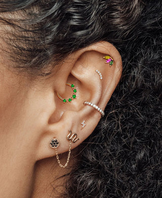 Styled ear with colorful studs, hoops and a connecting chain