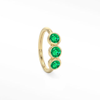 14K yellow gold trio seam ring with three round green bezel-set emeralds aligned along the hoop