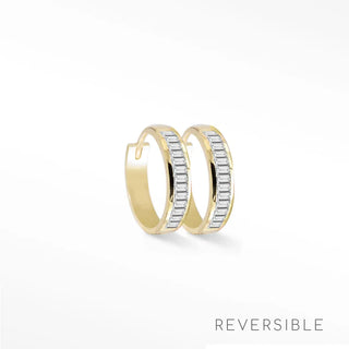 A pair of gold huggie hoop earrings with a row of baguette-cut clear stones on the front, shown on a clean white background with the word 'REVERSIBLE' in the bottom right corner.