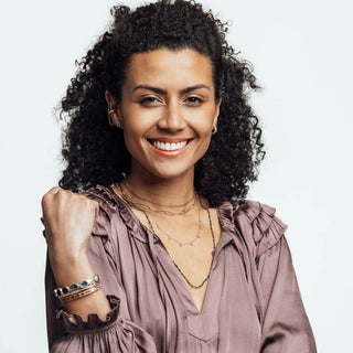A woman wears a mauve satin blouse with ruffled sleeves for group event booking by nina wynn jewelry designer
