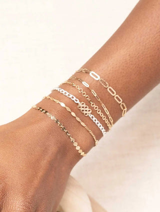 A collection of delicate gold and silver-toned chain bracelets worn on wrist book permanent jewelry with nina wynn appointment