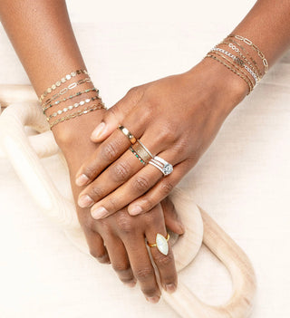 Lifestyle photo of layered permanent bracelets and rings on hands