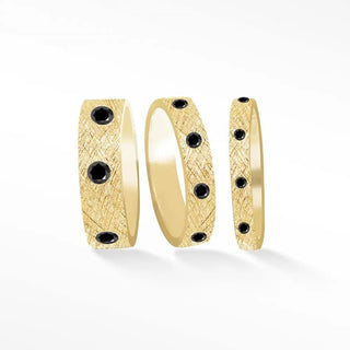 Gold wedding band with textured florentine 14k gold surface and embedded black diamonds in a diamond cigar band design