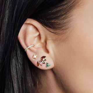 A gold-toned 14k yellow gold cartilage hoop earring with clear crystals paired with colorful gemstone studs from nina wynn