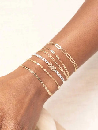 A collection of delicate gold and silver-toned chain bracelets worn on wrist book permanent jewelry with nina wynn appointment