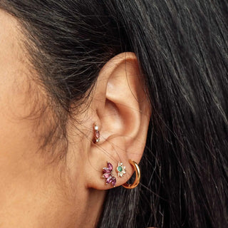 A gold-toned ear cuff with purple and emerald stones and crystals for nina wynn ear piercing denver jewelry