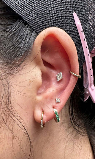 Cartilage and lobe ear piercings styled with diamond studs and green gemstone hoop on a real client in Denver