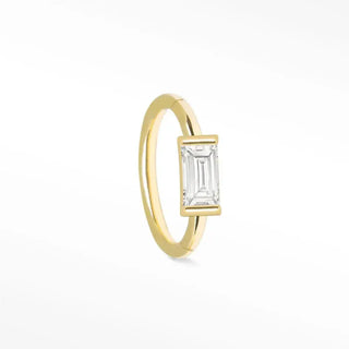 A delicate 14k yellow gold cartilage hoop earring featuring a diamond baguette in an elegant minimalist design