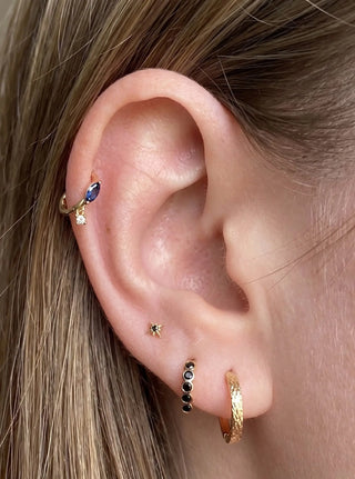 Cartilage hoop earrings in 14k gold featuring a blue sapphire marquise and dangling diamond charm. Discover regal