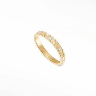 A 14k gold cigar band ring with a textured surface and three round band ring diamonds set along its side