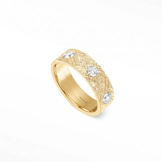 A 14k gold cigar band ring with a textured surface and three round-cut band ring diamonds set along its side