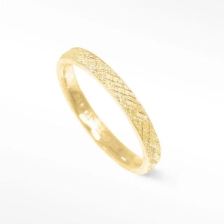 A delicate florentine 14k gold cigar band ring featuring a subtle textured pattern along its surface