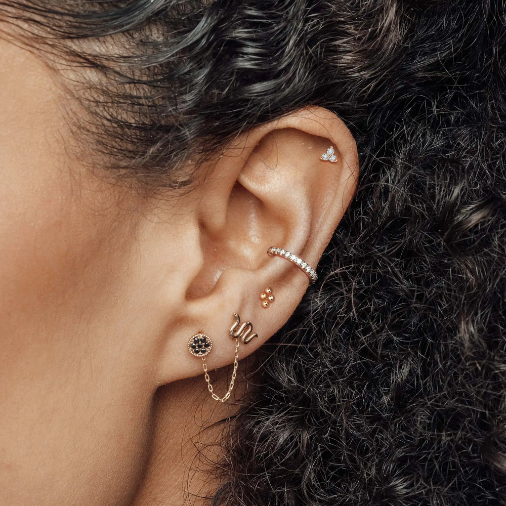 Curated ear featuring gemstone studs, a snake design, a hoop and a delicate chain.