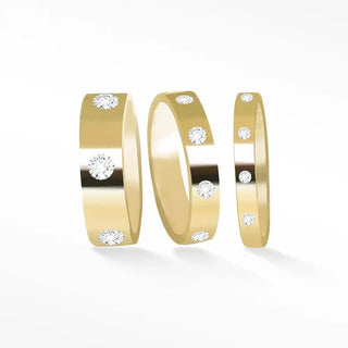Three 14k gold cigar band rings featuring varied widths with sparkling round diamonds along their surfaces