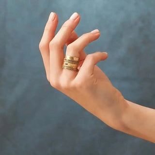 A stack of 14k gold cigar band rings with intricate beaded and textured bands worn on a finger