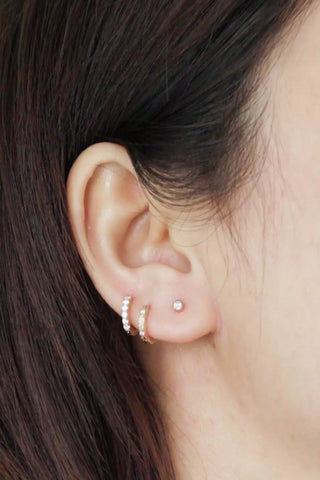 A delicate 14k yellow gold diamond huggie earrings set with small sparkling stones including matching stud