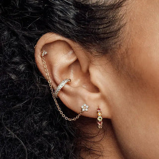 Gold-toned ear cuff with pavé stones and chain connected to diamond stud earrings buttercup 14k white with colorful gemstones