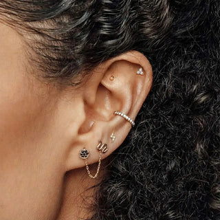 A delicate rose gold chain earring with a black silver charm paired with diamond stud earrings lightning bolt 14k white
