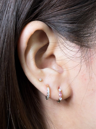 A delicate diana pink sapphire 14k gold reversible huggies 10mm hoop earring with clear stones and a central pink gem