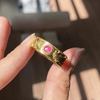 A 14K gold dragon phoenix ruby ring with intricate engravings and a central round natural pink ruby gemstone