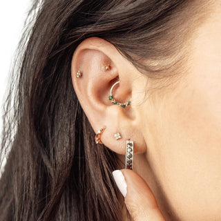 A delicate silver hoop earring with green gemstones and diamond accent by jewelry designer nina wynn at ear spa denver