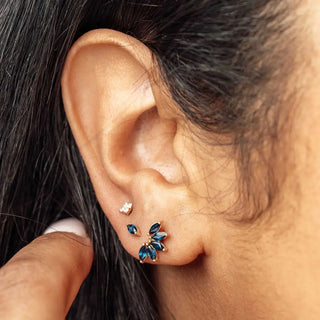 A gold toned ear stud with deep blue marquise gemstones in a leaf pattern by jewelry designer nina wynn for ear spa denver