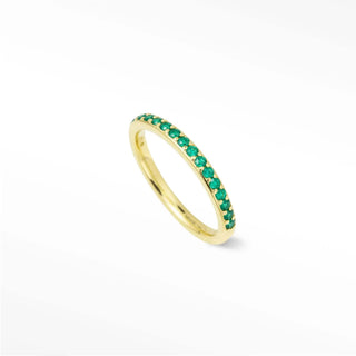 A delicate 14K gold emerald eternity band with vibrant green emerald stones called thea emerald eternity