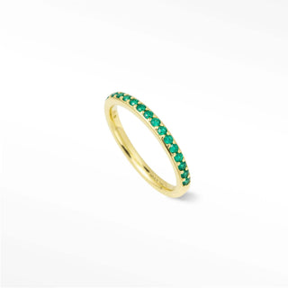 A delicate 14K gold emerald eternity band with vibrant green emerald stones called thea emerald eternity