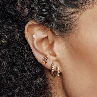 A delicate rose gold hoop earring with sparkling stones, complementing 14k yellow flat back earrings wynning studs