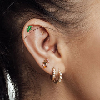Green leaf-shaped emerald earrings ear cuff with tiny gemstones in 14k yellow gold from The Wynning Studs