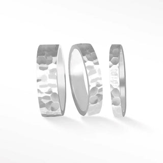 Three silver-toned cigar band ring hammer wedding bands with textured reflective hammered sterling silver surface