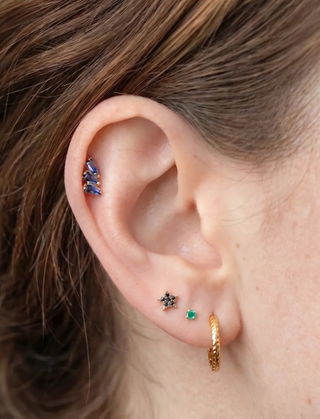 Gemstone earrings styled on an ear with other studs and hoops