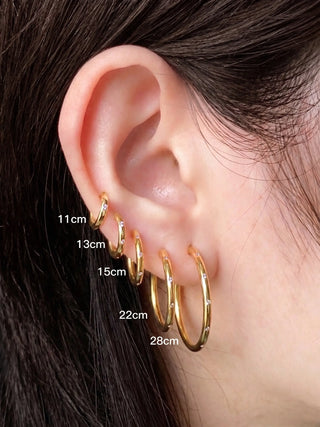 A set of five gold hoop earrings in varying sizes with small embedded stones from Ellie Gold Hoop Earrings Wynning Reversible Hoops