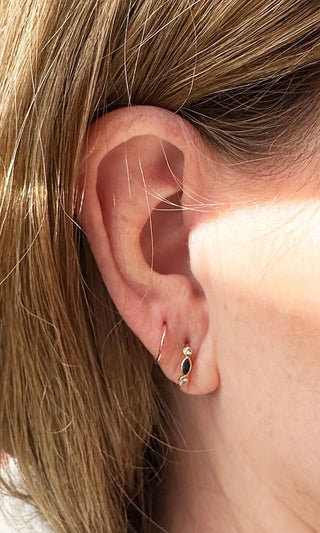 Gold-toned hoop earring with a black oval gemstone accent