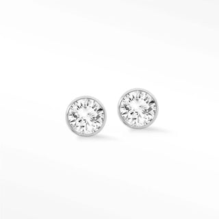 A pair of lab grown diamond studs bezel set in 14k white gold with a sleek silver-toned minimalist design