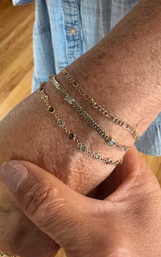 Mixed chain clasp-less permanent jewelry stacked for a textured wrist look in Denver.