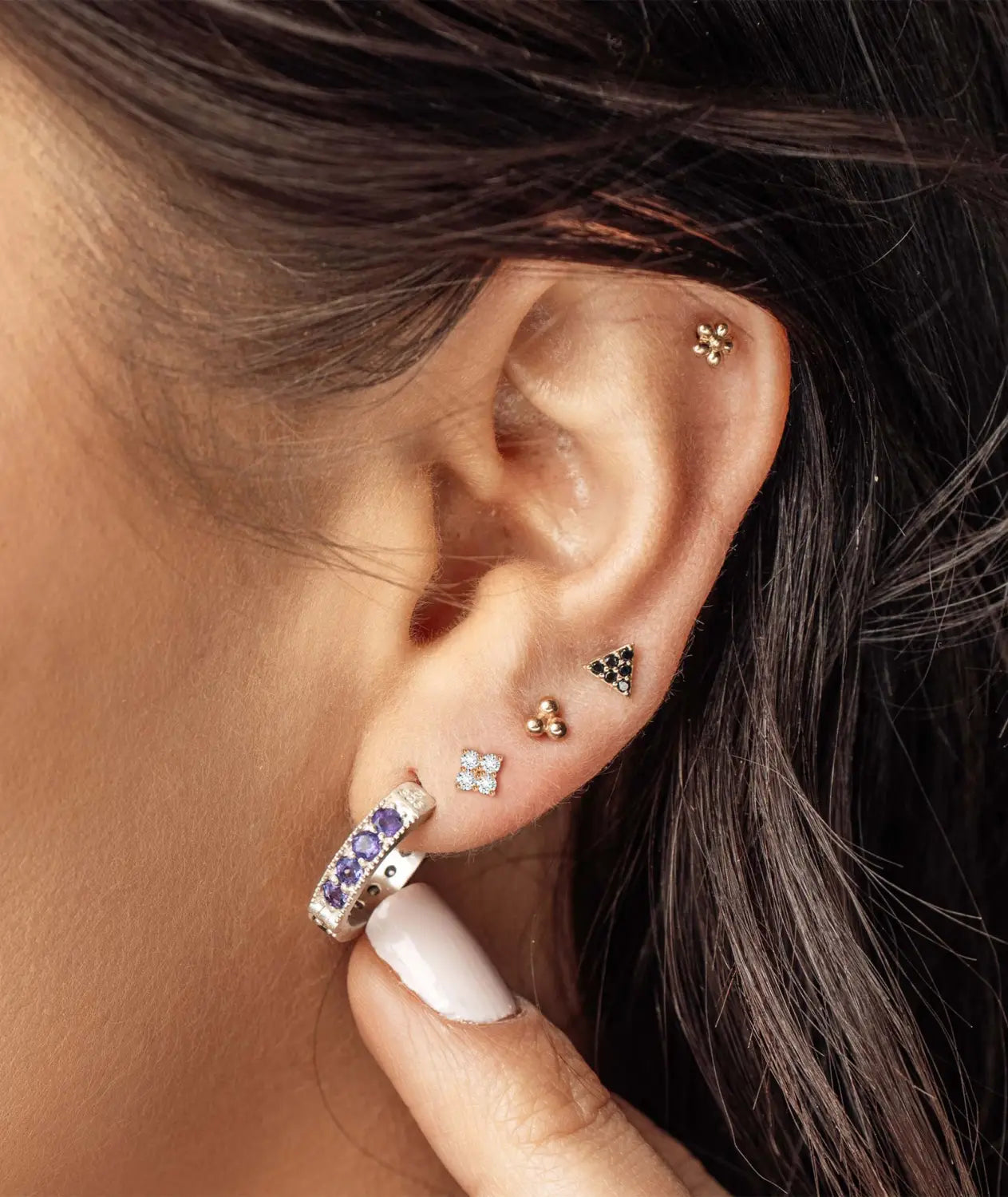 Multiple cartilage and lobe piercings arranged as a curated ear