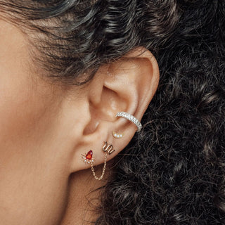 A delicate silver crescent moon ear cuff with sparkling stones complementing padparadscha sapphire earrings