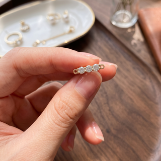 14K yellow gold diamond pave 3-stone bar connector held between fingers, featuring sparkling round diamonds and gold loop ends for permanent jewelry bracelets and necklaces.