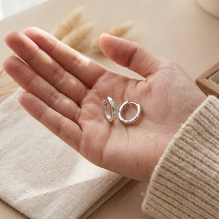 Hand holding Ellie 11mm sterling silver reversible hoops