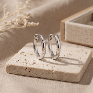 Pair of Ellie sterling silver hoops standing upright on a stone display
