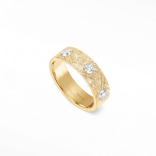 A 14k gold cigar band ring with a textured surface and three round-cut band ring diamonds set along its side