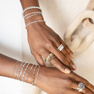 Wholesale Permanent Jewelry Supplies Houston: layered silver-tone bracelets with varied chain links and round accents.