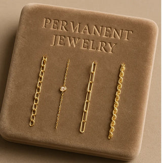 Four chain styles arranged on a tan tray embossed with Permanent Jewelry.